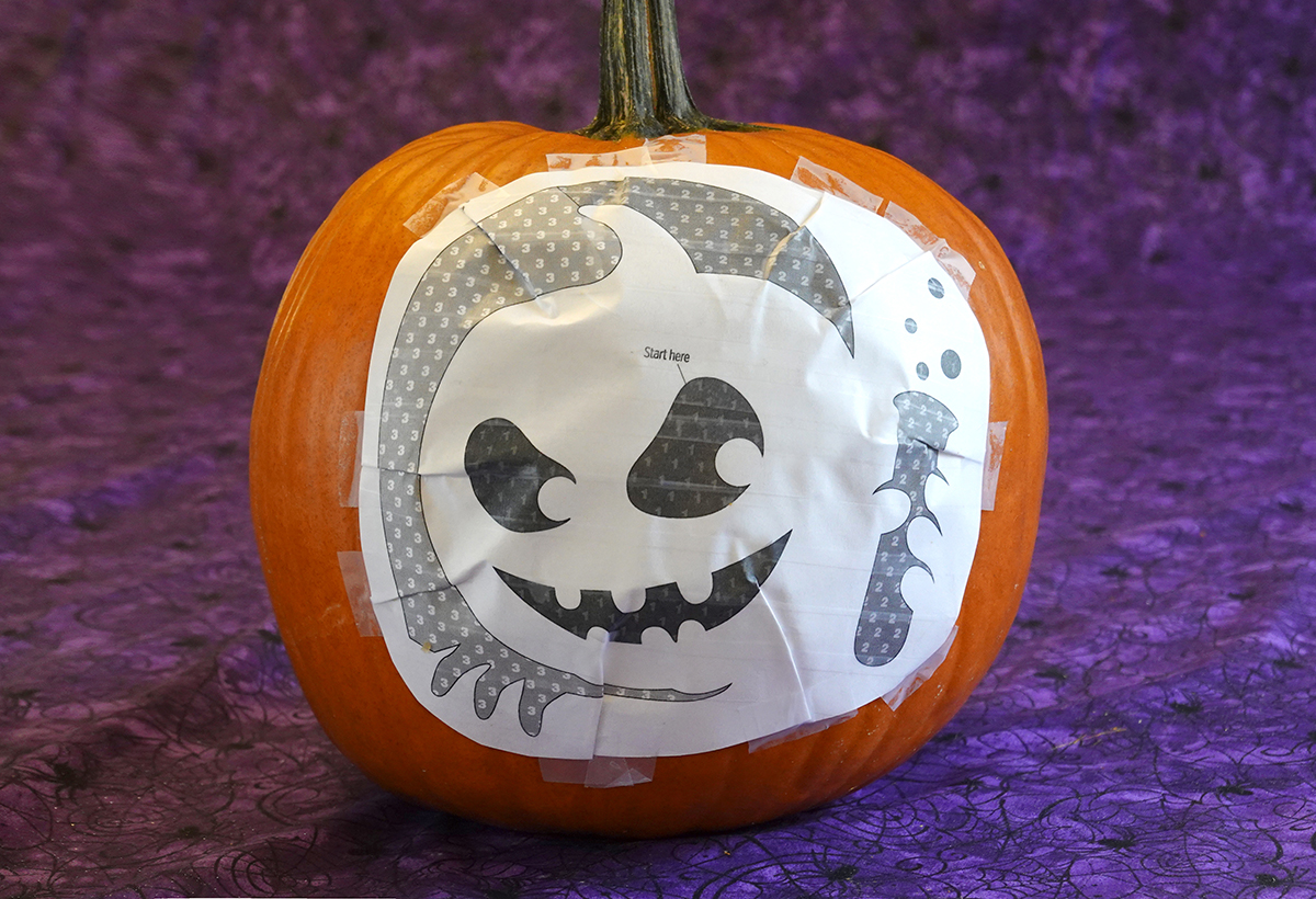 A taped pattern fitted around the front of a pumpkin