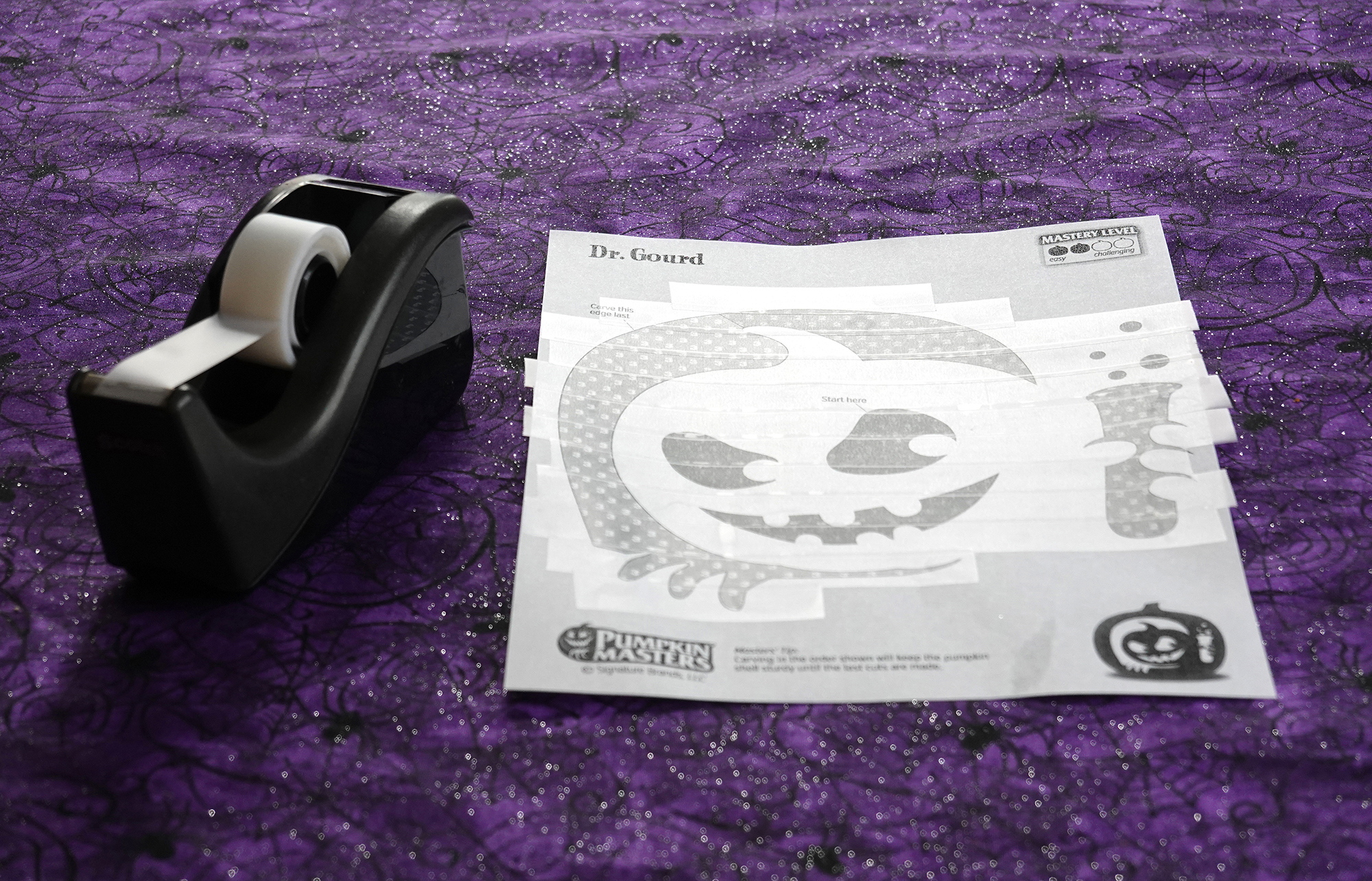 A Pumpkin Masters pattern covered in strips of clear tape next to a tape dispenser