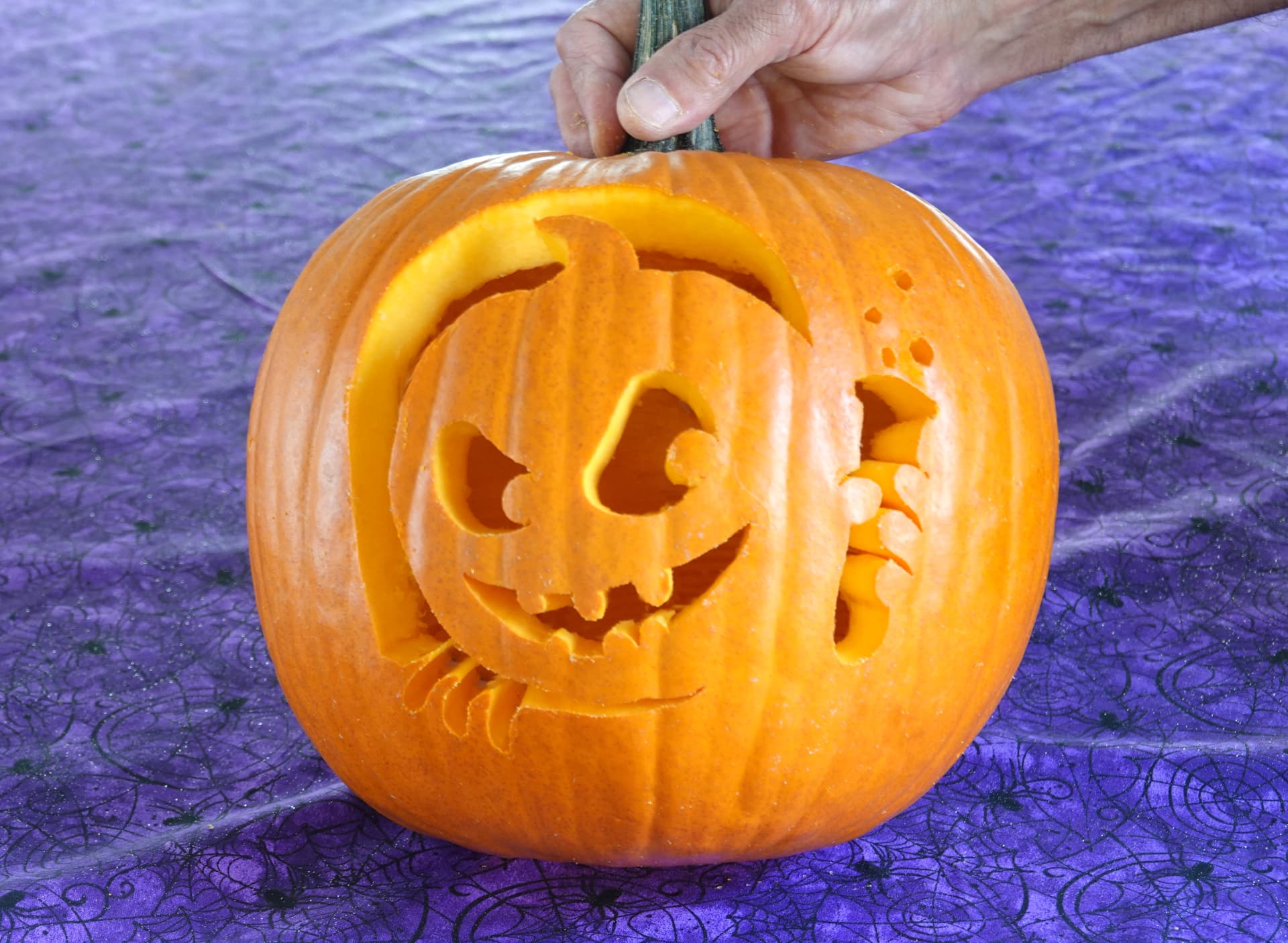 Mad scientist jack-o'-lantern carved from a Pumpkin Masters pattern, unlit, held by the stem